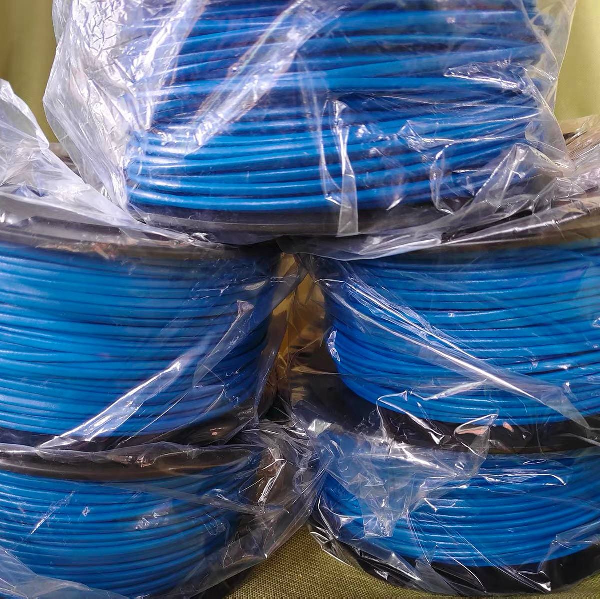 Stacked blue LHD thermal sensor cable spools sealed inside clear protective polybags, three rows shown from the front