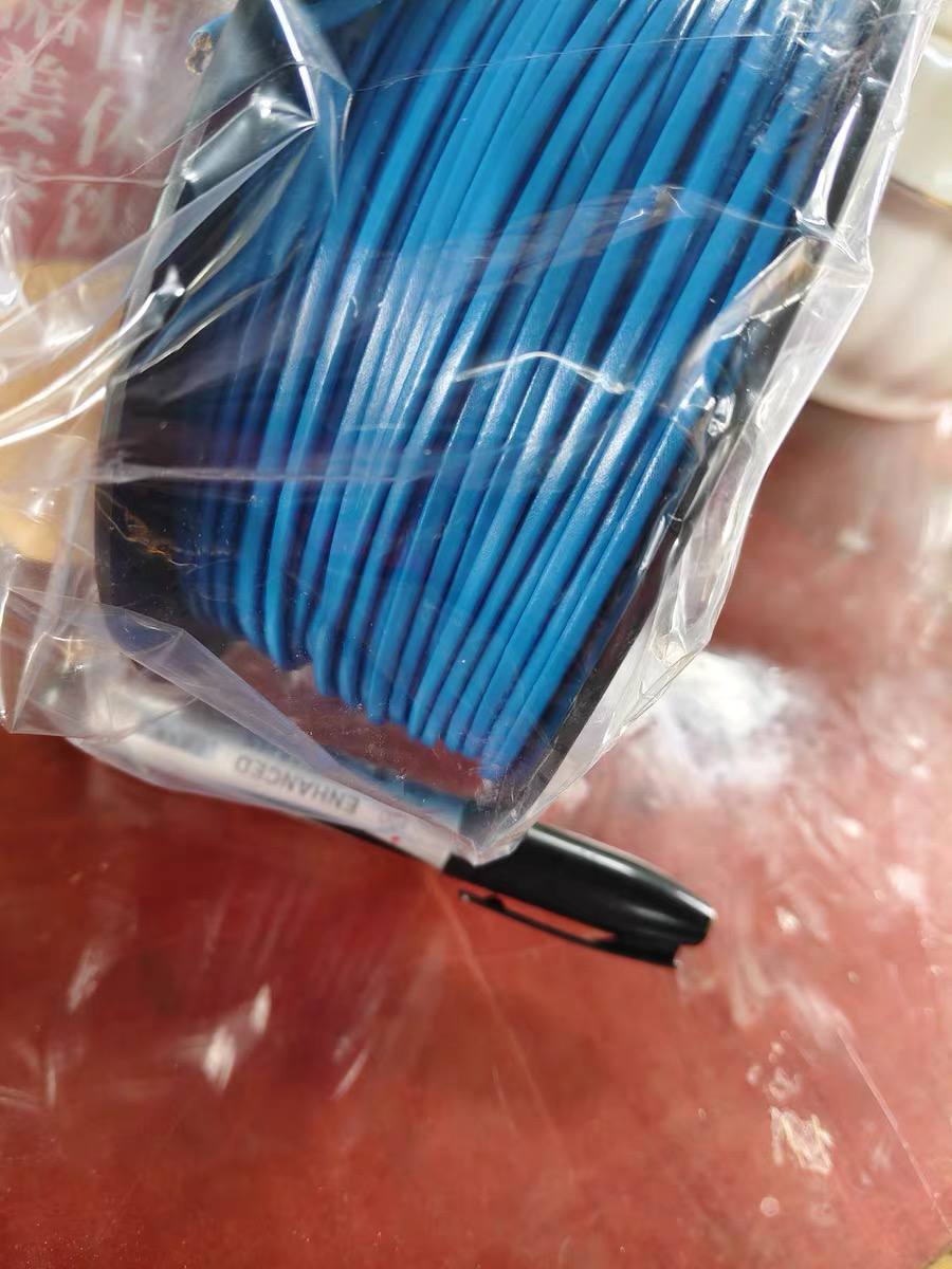 A blue LHD thermal sensor cable spool sealed inside a clear protective polybag, bottom edge showing a partially visible 'ENHANCED' label, photographed on a red workbench